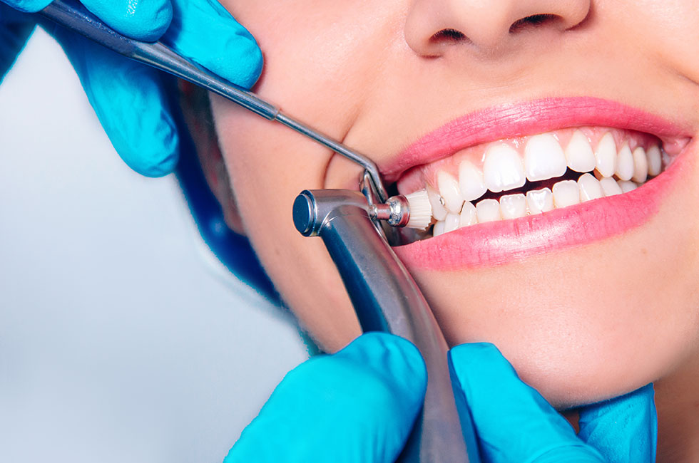 Close-up of dentist performing professional teeth cleaning using dental scaler and polishing tool in clinic